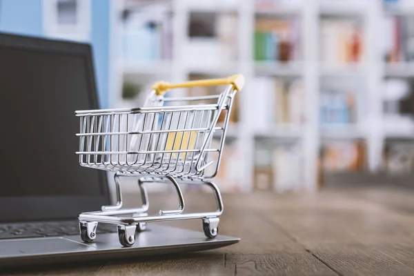 Miniature shopping cart and laptop on a desk — Stock Photo, Image