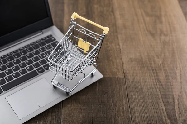 Miniatuur winkelwagentje en laptop op een bureau — Stockfoto