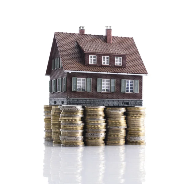 Model house with piles of coins as foundation — Stock Photo, Image