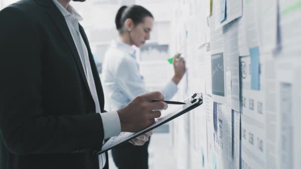 Gente de negocios revisando datos financieros en una pared — Vídeos de Stock