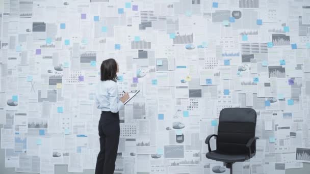 Businesswoman analyzing financial data on a wall — Stock Video