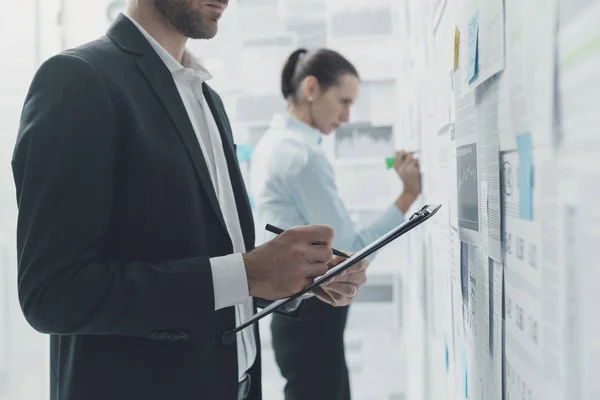 Geschäftsleute analysieren Finanzberichte an einer Wand — Stockfoto