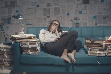 Yorgun iş kadını kanepede oturuyor ve sohbet ediyor.