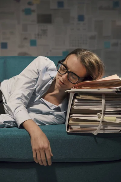 Стрессовая деловая женщина спит на диване с большим количеством бумажной волокиты — стоковое фото