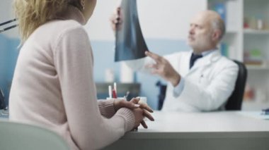 Doktor bir ziyarette hastanın röntgen görüntüsünü inceliyor.