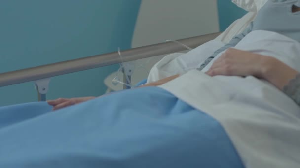 Ranna kobieta leżąca w szpitalnym łóżku z kołnierzem szyjnym i kroplówką. — Wideo stockowe