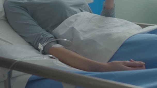 Young patient getting IV at the hospital and chatting with her phone — Stock Video