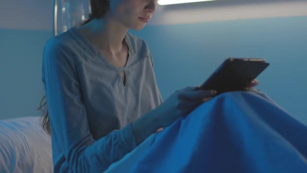 年轻病人躺在医院的床上，与平板电脑相连 — 图库视频影像