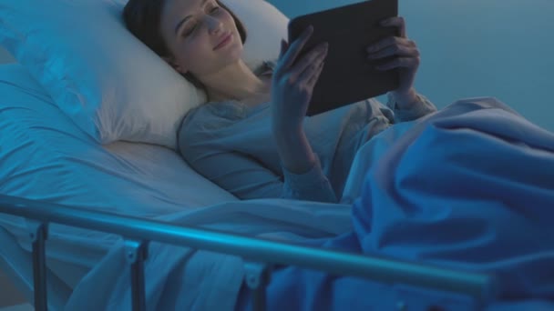 Junge Patientin liegt im Krankenhausbett und verbindet sich mit einem Tablet — Stockvideo