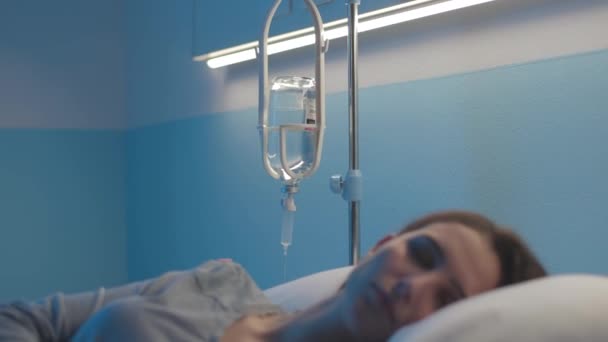 Mujer acostada en la cama del hospital y recibiendo terapia intravenosa — Vídeos de Stock