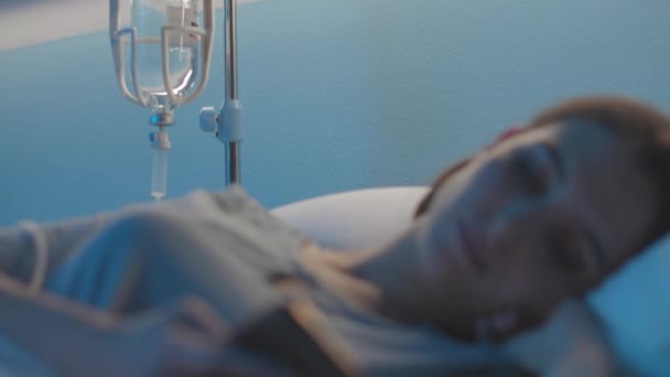 Νεαρή ασθενής ξαπλωμένη στο κρεβάτι στο νοσοκομείο και χρησιμοποιώντας το smartphone της — Αρχείο Βίντεο