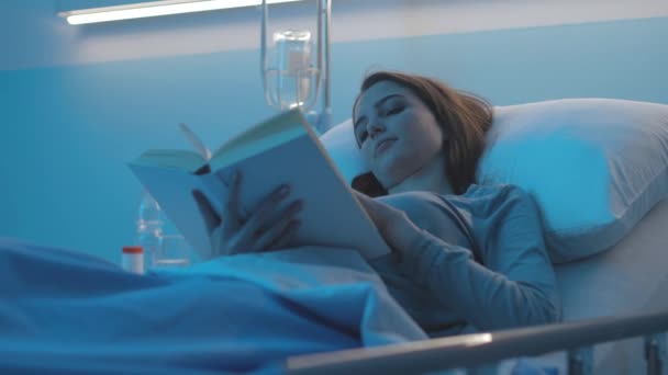 Hastane yatağında yatan ve kitap okuyan bir kadın hasta. — Stok video