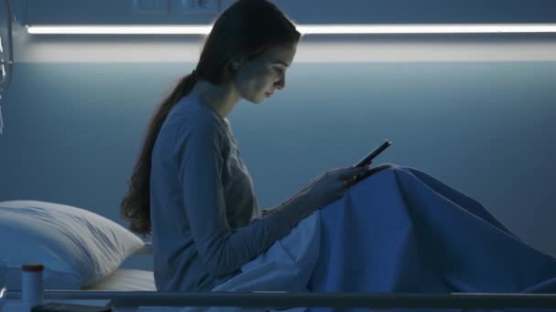 Mladý pacient ležící v posteli v nemocnici a spojující se s tabletou — Stock video