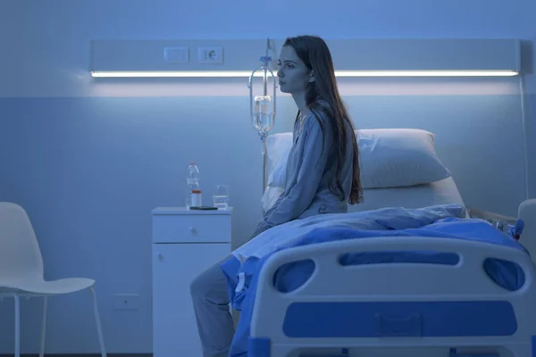 Triste paciente insomne sentado en la cama del hospital por la noche — Foto de Stock