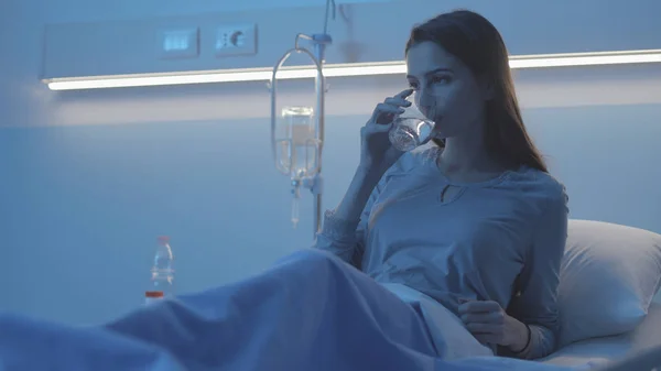 Patienten ligger i sängen på sjukhuset och dricker vatten — Stockfoto