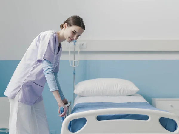 Junge angehende Krankenschwester arbeitet im Krankenhaus und stellt das Bett um — Stockfoto