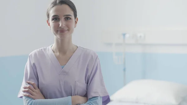 Junge Krankenschwester posiert neben einem Krankenhausbett — Stockfoto