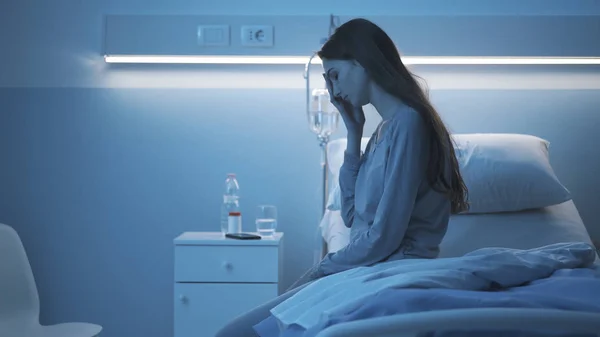 Triste paciente insomne sentado en la cama del hospital por la noche — Foto de Stock