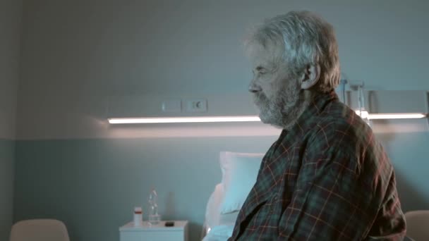 Smutný, beznadějný senior sedí sám v nemocniční posteli — Stock video
