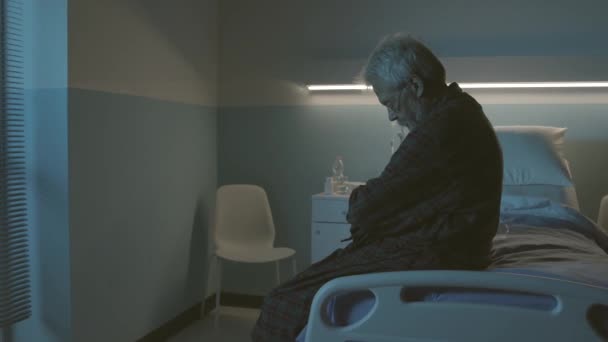Bir hastane yatağında yalnız, üzgün bir ihtiyar. — Stok video