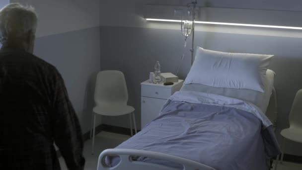Sorgsen ensam äldre man sitter på en sjukhussäng på natten — Stockvideo