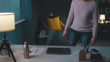 Genç bir kadın masa başında oturuyor ve işe başlıyor.