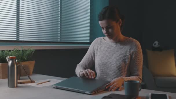 Νεαρή γυναίκα κάθεται στο γραφείο και αρχίζει την ημέρα εργασίας της — Αρχείο Βίντεο