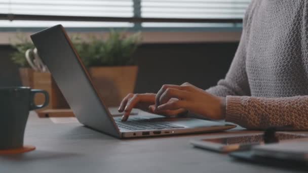 Egy nő ül az asztalnál és gépel a laptopjával. — Stock videók