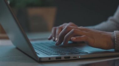 Masasında oturmuş laptopuyla yazı yazan bir kadın.