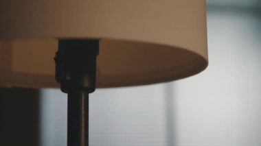 Kadın evinde masa lambasını yakıyor.