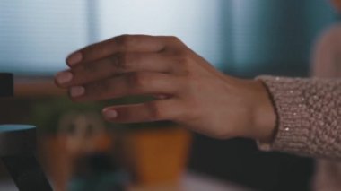 Kadın evinde masa lambasını yakıyor.