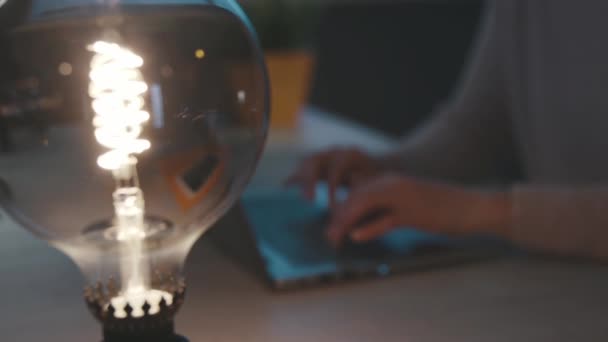 Женщина соединяется со своим ноутбуком и современной настольной лампой — стоковое видео