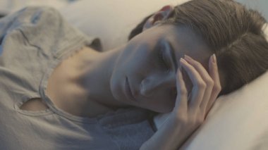 Genç bir kadın hasta, gece bir hastane yatağında uzanıyor ve uyuyor, sağlık hizmeti konsepti.