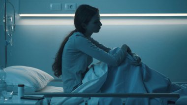 Üzgün kadın hasta gece hastanede yatıyor, uykusuz, yalnız ve endişeli.