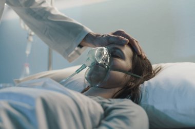 Hastanede yatan bir hasta gece yatarken, bir doktor onunla ilgileniyor ve alnına dokunuyor.