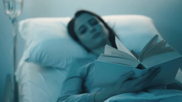 Genç Uykusuz Kadın Gece Hastane Yatağında Uzanıp Kitap Okuyor — Stok fotoğraf