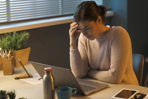 疲倦的年轻女人坐在办公桌前 用笔记本电脑工作 头疼得厉害 — 图库照片
