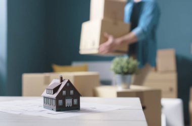 İnsanlar yeni bir eve taşınıyor, ön planda proje ve model ev, ev yenileme ve taşınma konsepti