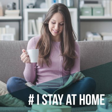Kanepede oturup kitap okuyan mutlu genç bir kadın: Coronavirus önleme için sosyal medya kampanyasında evde kalıyorum