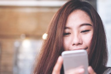 Asyalı kız ile akıllı telefon kullanarak gülen yüz 