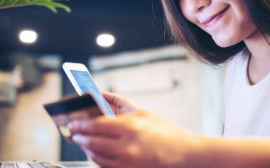 Kredi kartı tutan ve akıllı telefon kullanan kadın