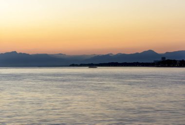 Dağlar ve deniz üzerine koyu renkli günbatımı