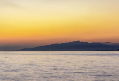 Dağlar ve deniz üzerine koyu renkli günbatımı