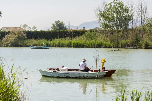 Pescador en un barco. Laguna de agua dulce en Estany de cullera. Valencia, España — Foto de Stock