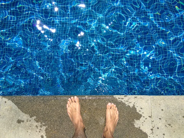 Mans naked foot standing on edge of bright blue swimming pool. — Stock Photo, Image