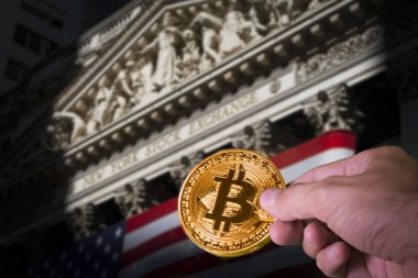 Bir bitcoin ve bulanık Nyse arka planda tutan el