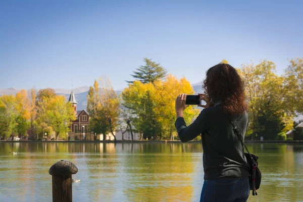 Mujer joven tomando una foto de colores otoñales y reflexionando sobre el agua del estanque Puigcerdas — Foto de Stock