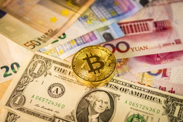 Moeda bitcoin dourada sobre notas de dólar, euro e yuan — Fotografia de Stock