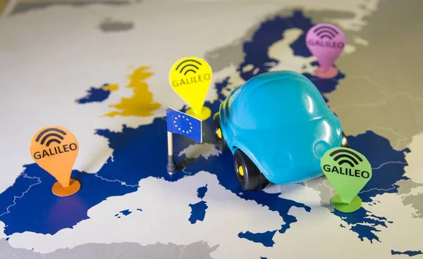 Игрушечная машина, значок Галилео и смартфон над картой ЕС. Метафора системы Галилея — стоковое фото