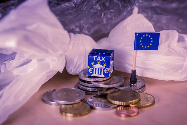 Mapa de la UE con monedas en euros y una bolsa de plástico que simboliza la regulación fiscal europea del plástico . — Foto de Stock